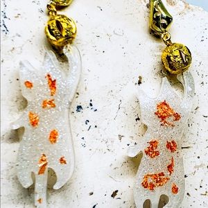 White playful cat dangles with gold ball